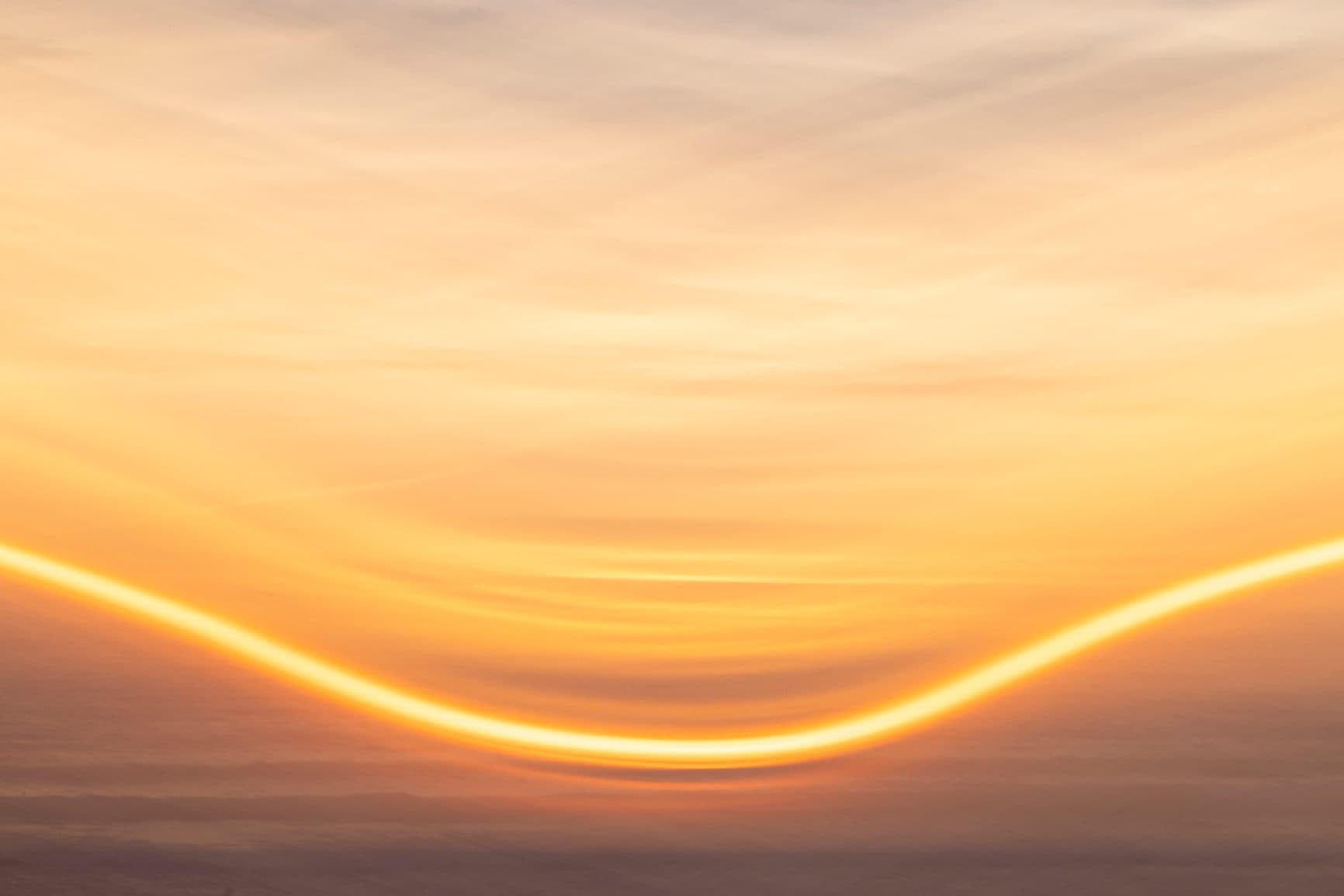 Golden light arc across a sunset horizon
