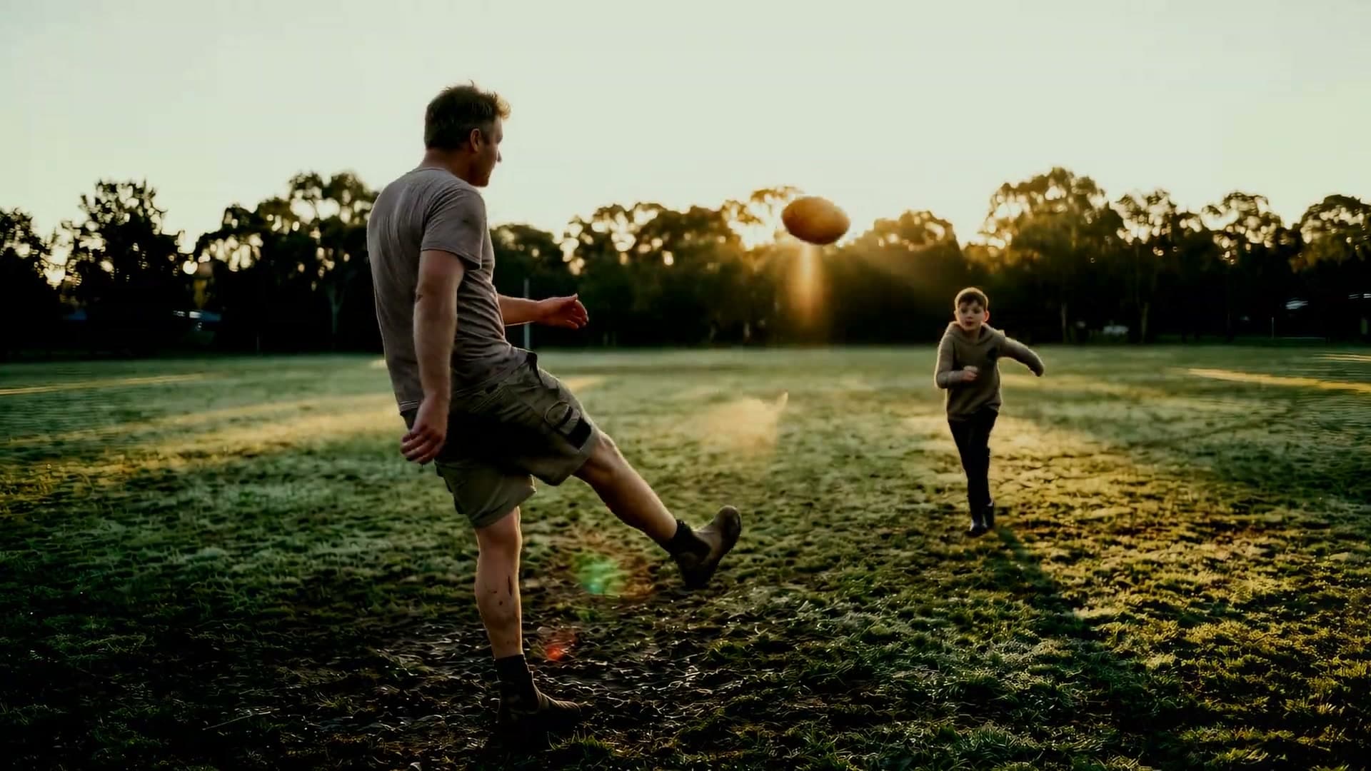 Everyday people at first light: a father kicking a football with his son, a woman sprinting with her dog, a surfer paddling out, a cyclist climbing a country road, a man rock-hopping across creek stones, a man running up coastal steps